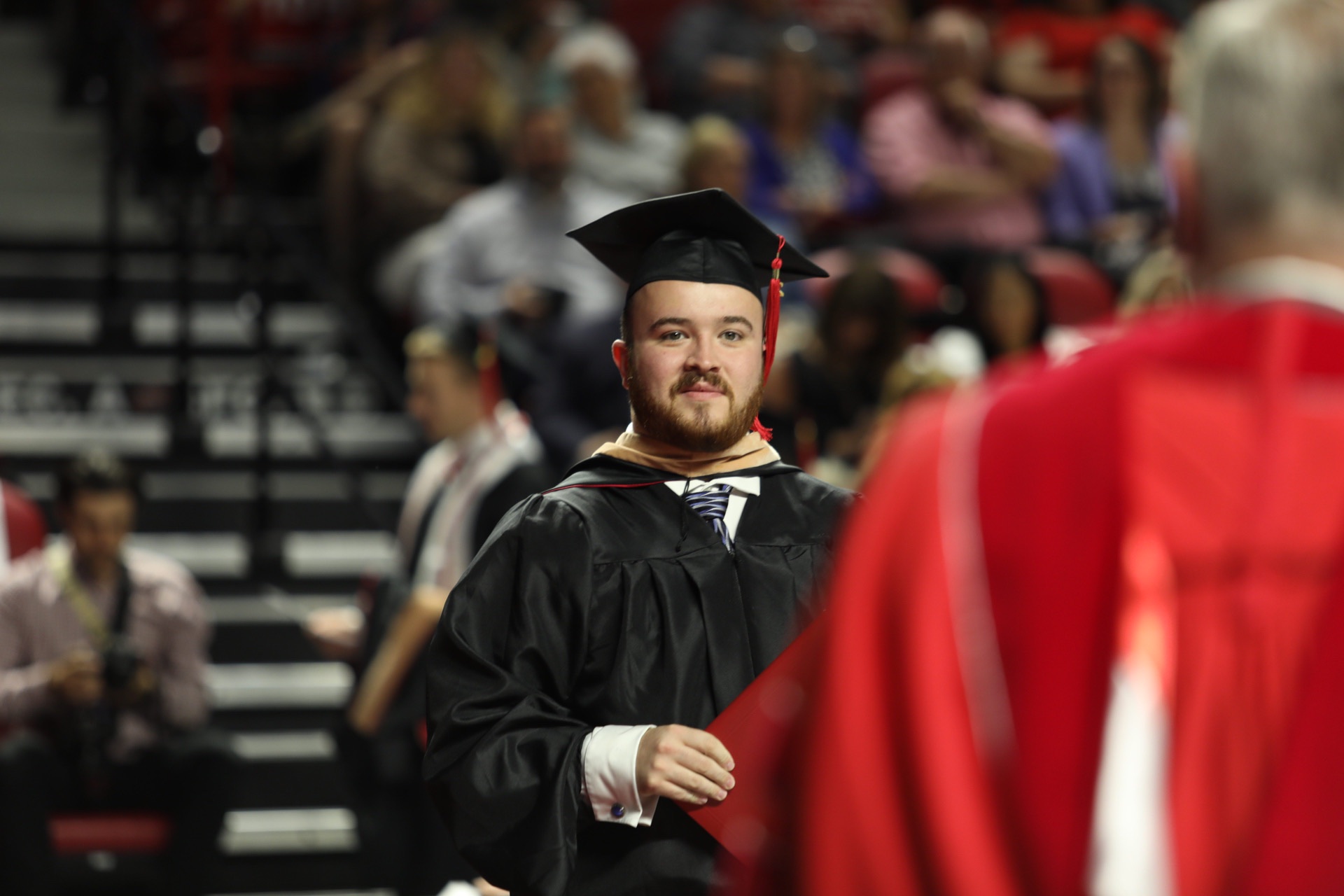 An MBA student walks at graduation.