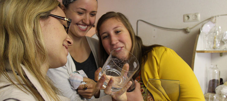 3 women looking at a glass together.