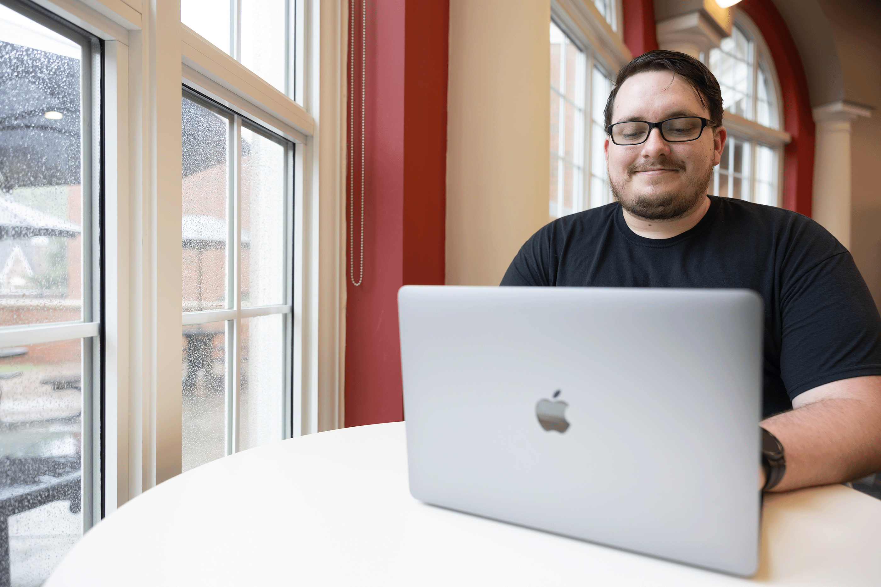 Student working on a laptop near a window in the student success center.