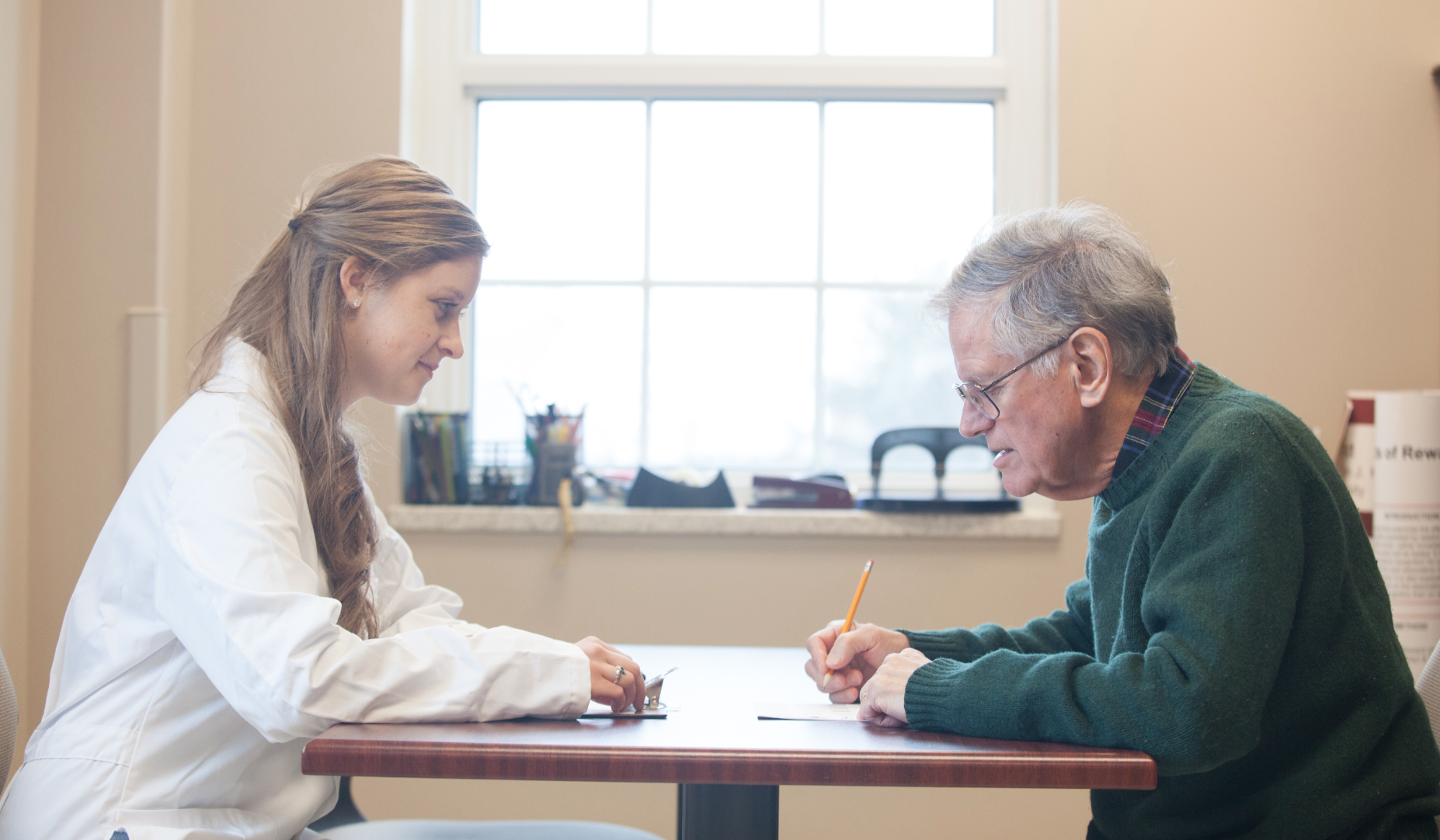 A WKU student sits across the table from a man and conducts a cognition study..