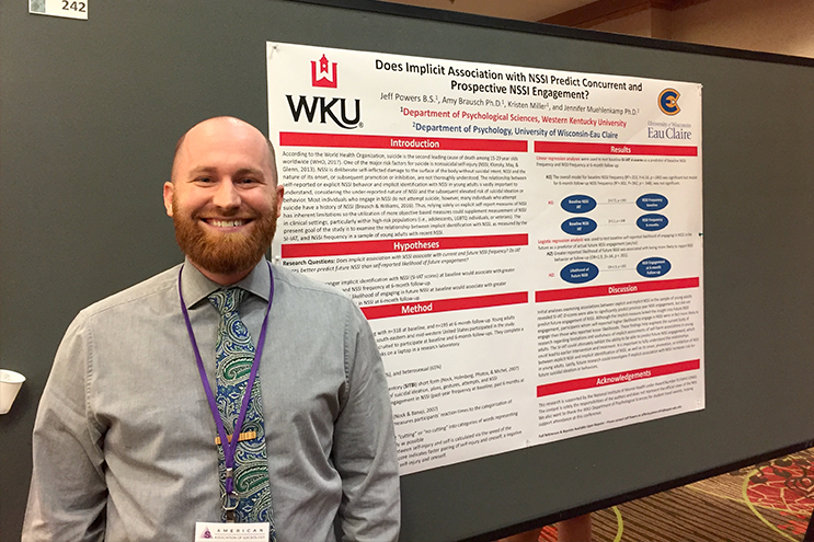 WKU student poses in front of poster presentation.