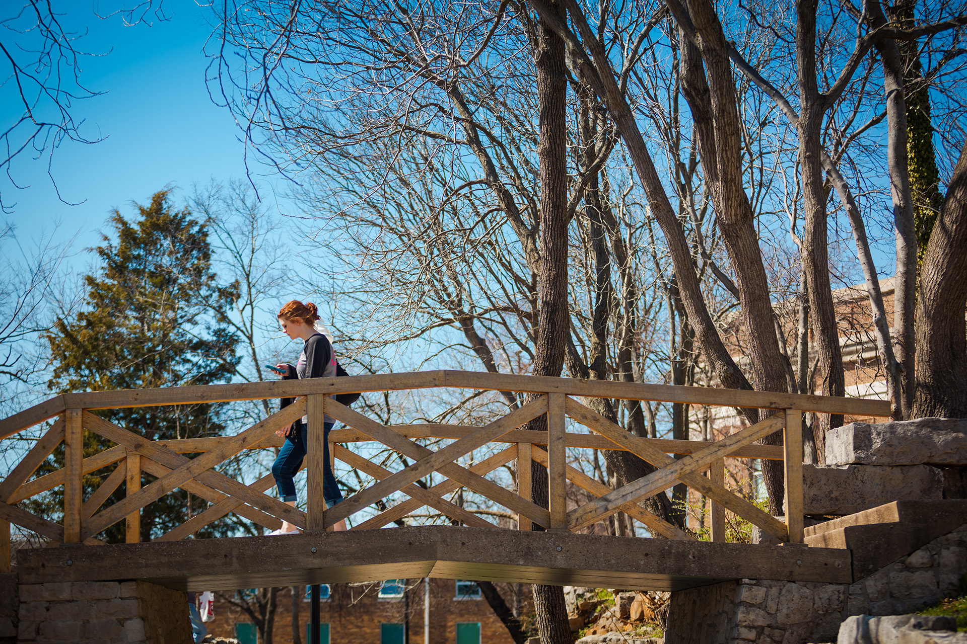 Student in Organizational Supervision crossing a bridge on the WKU campus.