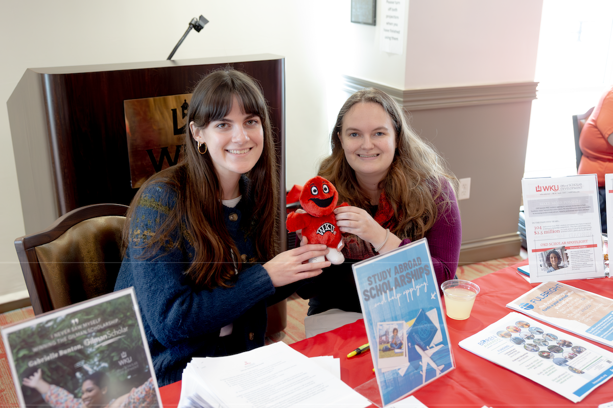 Two WKU students sit at a study abroad fair.
